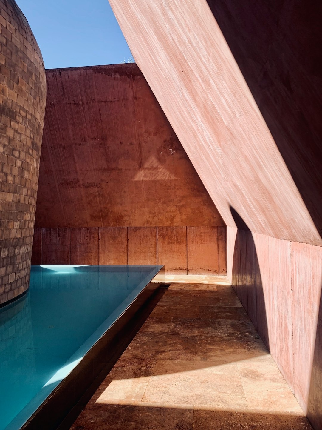 Geometric swimming pool surrounded by textured concrete and stone walls.